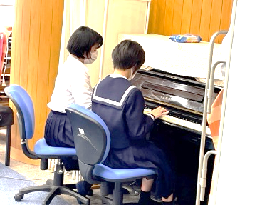 文化総合部がピアノの連弾をしている写真
